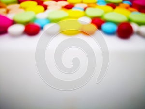 Medication and healthcare concept. Heap of colorful tablets medicine. Isolated on white background, blurred focus and copy space.