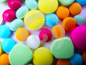 Medication and healthcare concept. Heap of colorful tablets medicine. Isolated on white background, blurred focus and full frame.