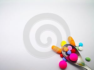 Medication and healthcare concept. Many colorful tablets of medicine, that are in silver spoon. Isolated on white