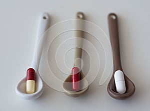 medication pills inside ceramic spoons. drugs, antibiotics, analgesics, narcotics