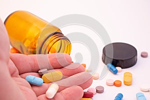 Medications in the form of pills and capsules on a white background. Hand of a man holding colored pills