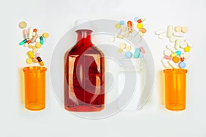 Medications spilling from a variety of bottles, top view on white