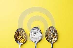 Medications vitamins tablets and pills in spoon. Yellow background. Copy of the space