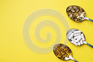 Medications vitamins tablets and pills in spoon. Yellow background. Copy of the space