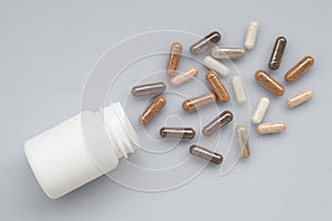 Medicinal capsule spill out of a plastic bottle on a light surfa