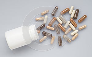 Medicinal capsule spill out of a plastic bottle on a light surfa