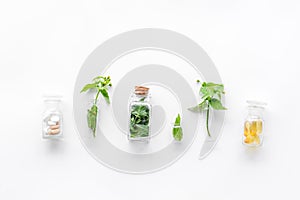 Medicinal herb in bottles on white background top view copyspace