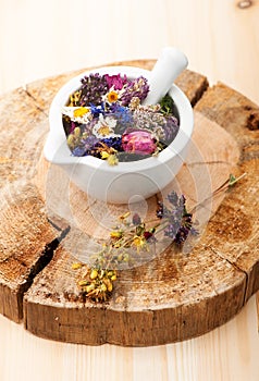 Medicinal herbs and flowers in a glass mortar.