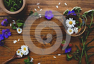 Medicinal herbs and strawberries, decoction of chamomile, yarrow and mint, tea. on a wooden background