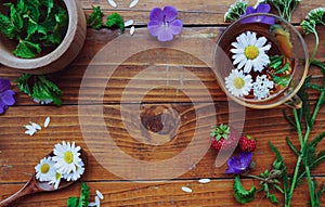 Medicinal herbs and strawberries, decoction of chamomile, yarrow and mint, tea. on a wooden background