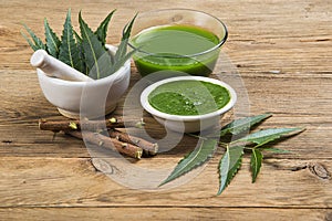 Medicinal Neem leaves in mortar and pestle with neem paste, juice and twigs