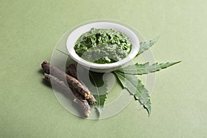 Medicinal Neem leaves with paste in bowl and twigs