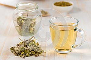 Tea in glass cup with dried herb.