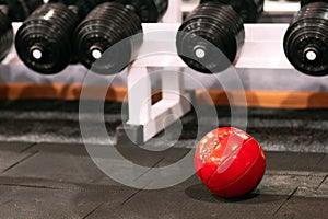 Medicine ball under dumbbells rack at gym