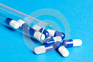 Medicine blue capsules pills in the test tube on blue background. Copy space. Medical background, template