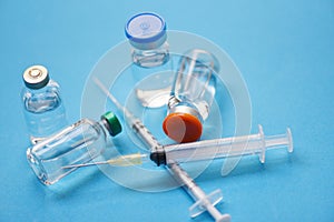 Medicine bottles glass and syringe injection needle on blue background - Medication drug bottle equipment medical tool for nurse