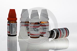 Medicine bottles with homeopathic beads in various dosages and active ingredients. The bottles have red and white caps and are iso