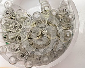Medicine capsules in a plastic white glass. ampoules filled with liquid, stacked together. drug therapy, drug treatment