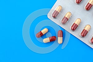 Medicine in capsules and in a tablet on a blue background.