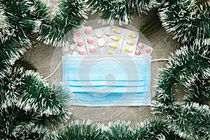 Medicine christmas new year concept during coronavirus covid time. Top view of medical pills with protective mask and fir-tree on