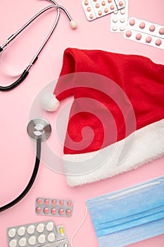 Medicine christmas new year concept during coronavirus covid time. Top view of medical pills with santa hat and stethoscope on