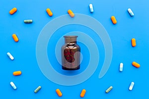 Medicine. Color capsules near pill bottle on blue background top view copy space