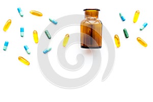 Medicine. Color capsules near pill bottle on white background top view copy space