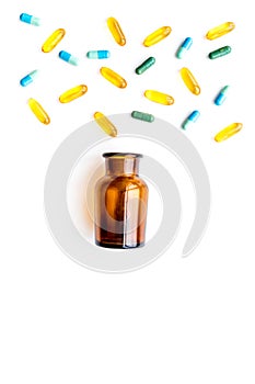 Medicine. Color capsules near pill bottle on white background top view copy space