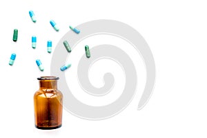 Medicine. Color capsules near pill bottle on white background top view copy space