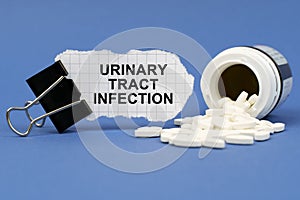 On the blue surface lies a jar of pills and a clip with paper on which is written - Urinary tract infection