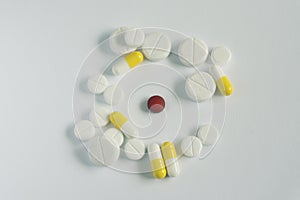 Medicine concept .red pill in circle of other white and yellow pills