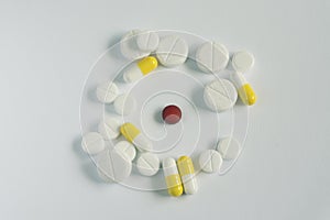 medicine concept .red pill in circle of other white and yellow pills