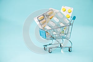 Medicine concept. Various capsules, tablets and medicine in shop trolley on a blue background. Pills concept. Buy