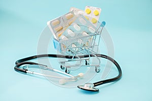 Medicine concept. Various capsules, tablets and medicine in shop trolley on a blue background. Pills concept. Buy