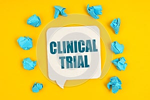 On a yellow background, blue pieces of paper and a sign with the inscription - CLINICAL TRIAL photo