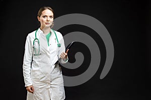 Medicine Concepts. Portrait of Professional Female GP Doctor Posing in Doctor`s Smock and Endoscope Against Black