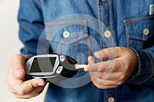 Medicine, diabetes, glycemia, health care and people concept - close up of man checking blood sugar level by glucometer photo