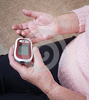 Medicine, diabetes, glycemia, health care and people concept - close up of woman checking blood sugar level by