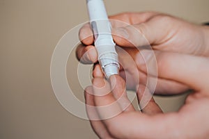 Medicine, diabetes, glycemia, healthcare and people concept - close up of a man`s hands using a lancet on his finger to check