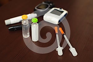 Medicine, diabetes and health care concept - close up of blood sugar test stripe, glucometer, insulin pen and other