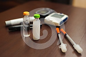 Medicine, diabetes and health care concept - close up of blood sugar test stripe, glucometer, insulin pen and other