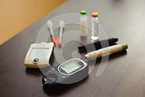 medicine, diabetes and health care concept - close up of blood sugar test stripe, glucometer, insulin pen and other