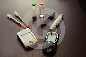 medicine, diabetes and health care concept - close up of blood sugar test stripe, glucometer, insulin pen and other