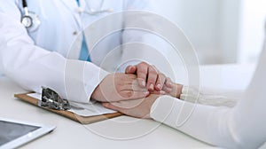 Medicine doctor hand reassuring her female patient closeup. Medicine, comforting and trusting concept in health care