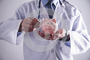 Medicine doctor holding piggy bank. Health Insurance