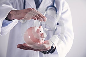 Medicine doctor holding piggy bank. Health Insurance