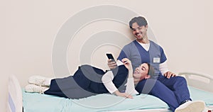 Medicine, doctor or nurse on break with smartphone on hospital bed with smile, laugh and happy. Man, woman or friends