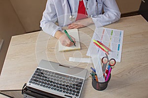 Medicine doctor`s working table. Doctor sits in a medical office in the clinic and writes medical history
