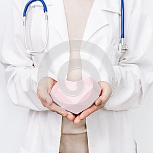 Medicine doctor in white coat holds pink heart. Healthcare and medical concept