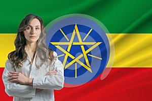 Medicine in Ethiopia Happy beautiful female doctor in medical coat standing with crossed arms against the background of